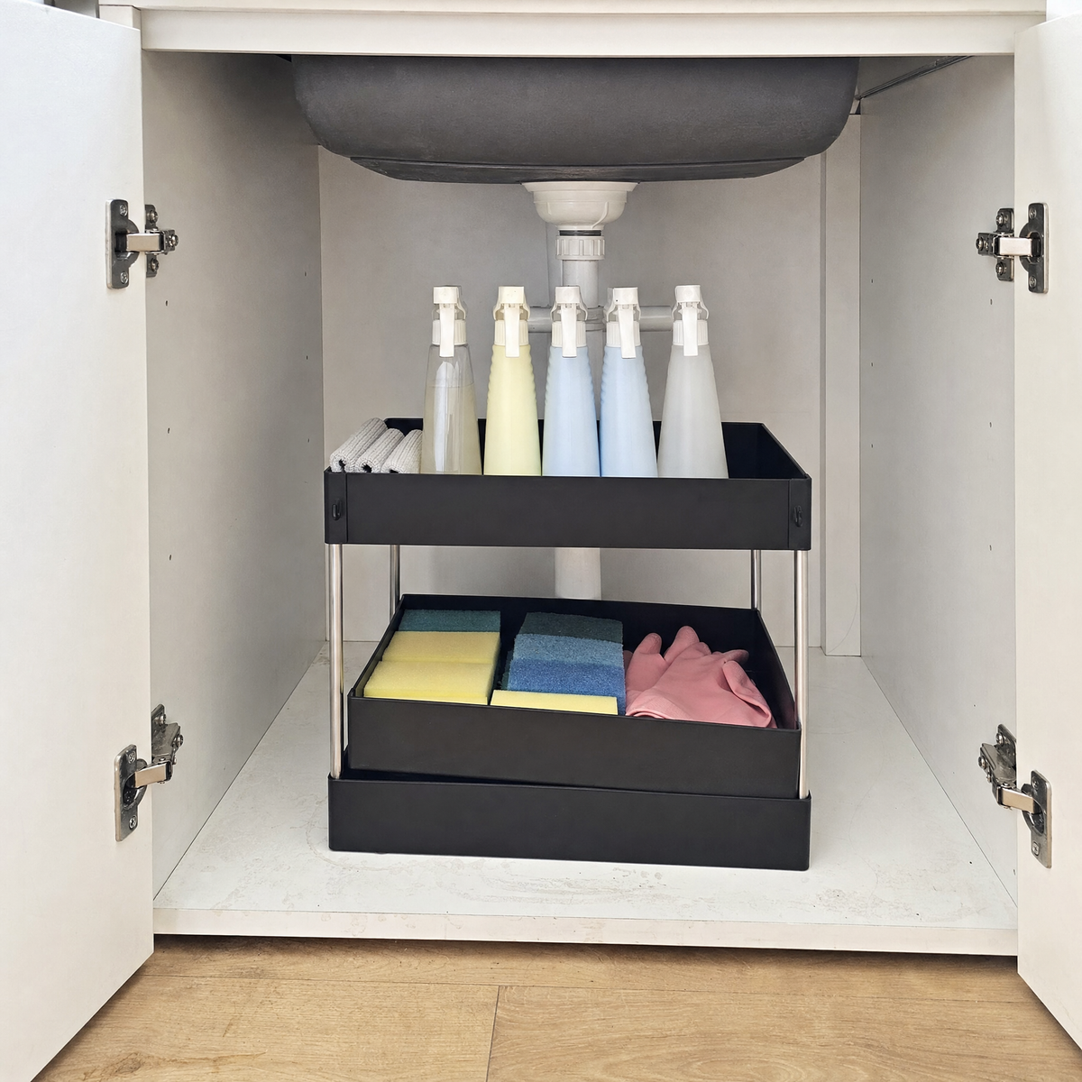 Two-tier under sink organizer installed in a kitchen cabinet with pull-out drawers holding cleaning supplies